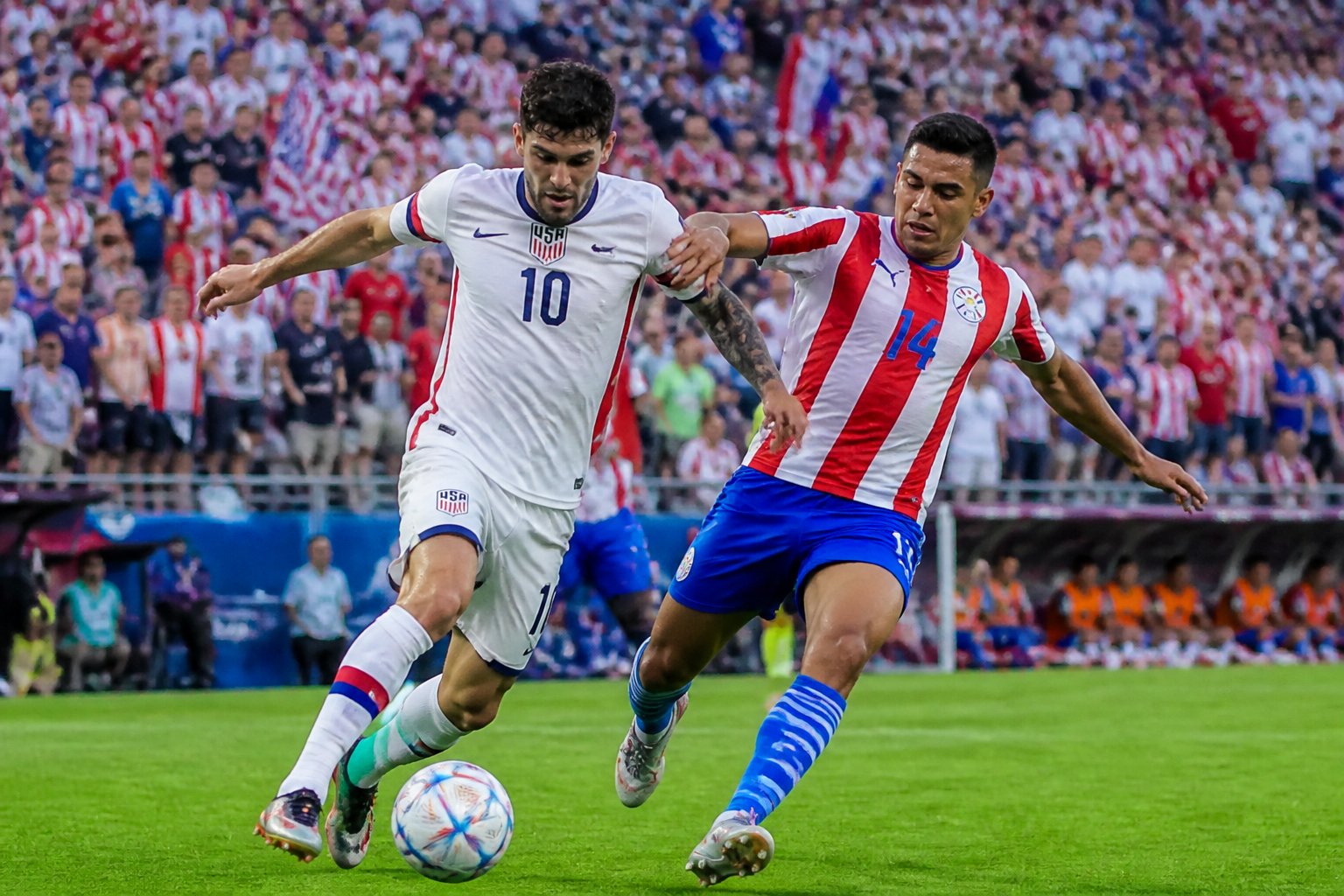 ABD ve Paraguay futbol takımları arasında Dünya Kupası maçında saha üzerinde mücadele eden oyuncular ve dolu tribünler.