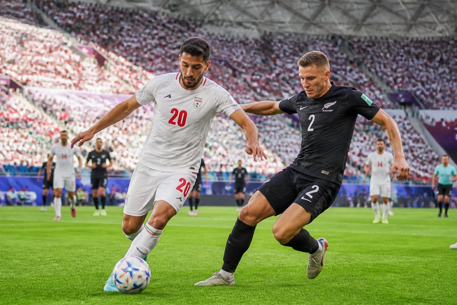 İran ve Yeni Zelanda futbol takımları, kalabalık bir stadyumda Dünya Kupası maçında mücadele ediyor.