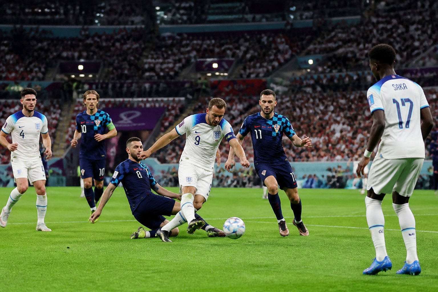 İngiltere ve Hırvatistan arasında Dünya Kupası maçında futbolcular saha içinde mücadele ediyor.
