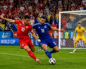 İsviçre ve Bosna Hersek takımları arasında Dünya Kupası maçında iki futbolcu top için mücadele ediyor, kalenin önünde yoğun bir atmosfer var.