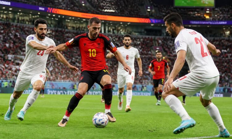 Belçika ve İran takımlarının büyük bir kalabalık önünde futbol maçı oynadığı sahne.