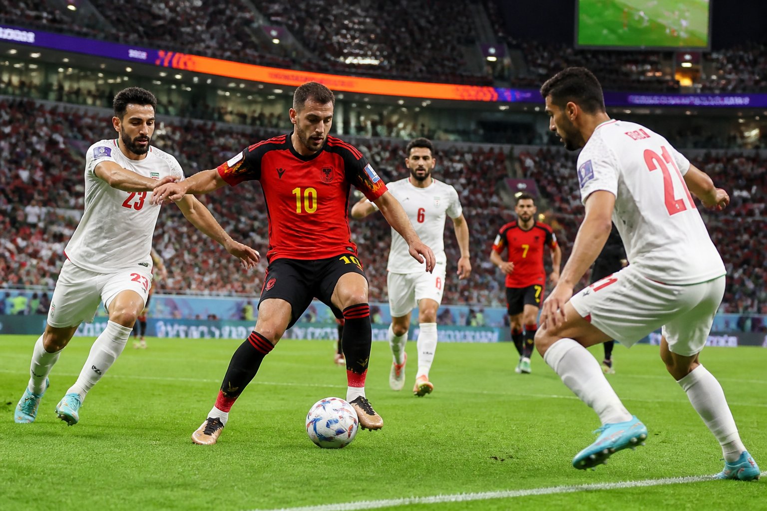 Belçika ve İran takımlarının büyük bir kalabalık önünde futbol maçı oynadığı sahne.