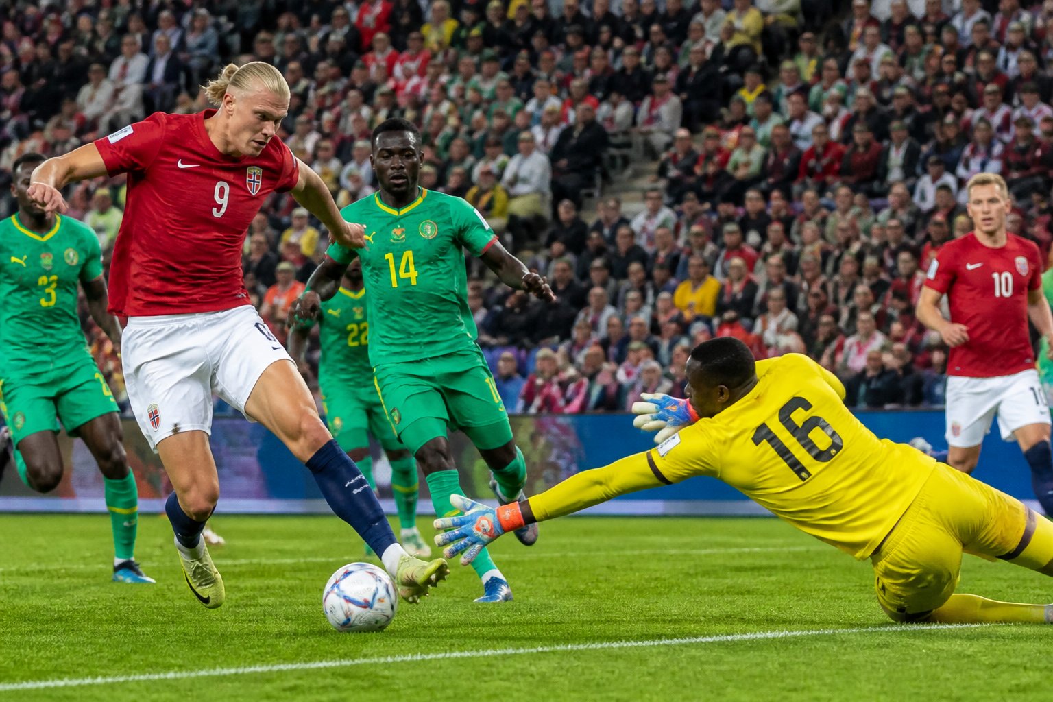 Norveç ve Senegal takımlarının futbolcularının bir Dünya Kupası maçında kaleye yakın alanda mücadele ettiği, kalecinin topu kurtarmaya çalıştığı bir sahne.
