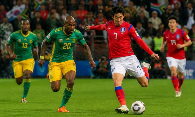 Güney Afrika ve Güney Kore futbol takımları arasında bir Dünya Kupası maçında oyuncular top için mücadele ediyor.