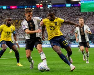 Ekvador ve Almanya futbol takımları, kalabalık bir stadyumda Dünya Kupası maçında mücadele ediyor.