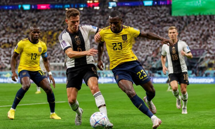 Ekvador ve Almanya futbol takımları, kalabalık bir stadyumda Dünya Kupası maçında mücadele ediyor.