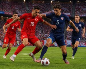 Türkiye ve ABD arasında geçen bir futbol maçında iki oyuncu top için mücadele ediyor, arka planda kalabalık bir stadyum ve taraftarlar yer alıyor.