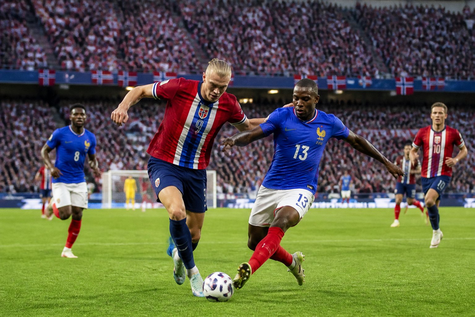 Norveç ve Fransa takımları arasında Dünya Kupası maçında futbolcular sahada mücadele ediyor, tribünler dolu ve seyirciler maçı izliyor.