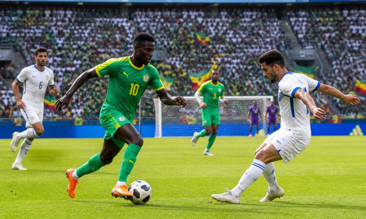 Senegal ve Irak arasında Dünya Kupası maçında sahada topa sahip olan oyuncular ve arka planda dolu tribünler.