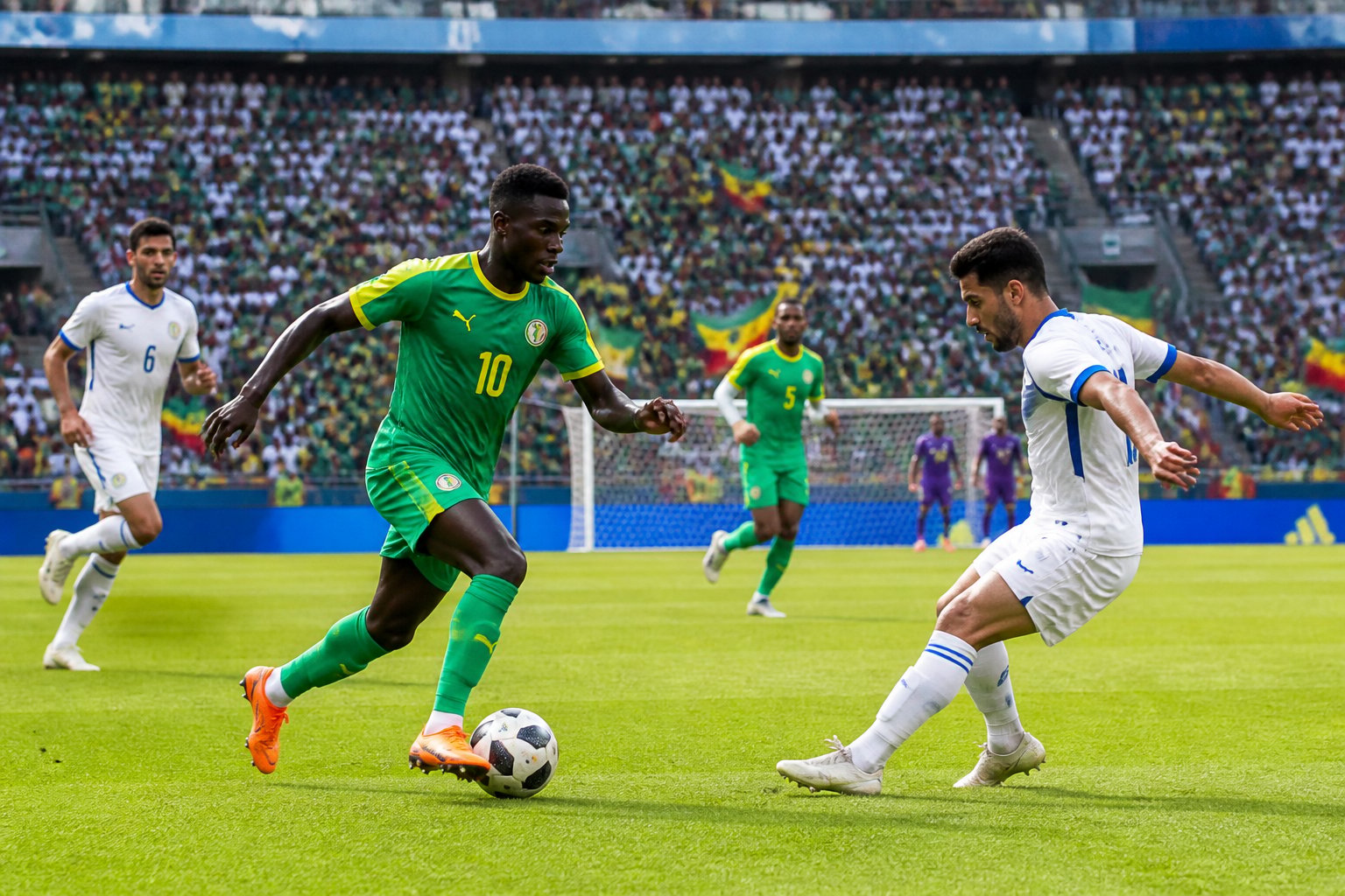 Senegal ve Irak arasında Dünya Kupası maçında sahada topa sahip olan oyuncular ve arka planda dolu tribünler.