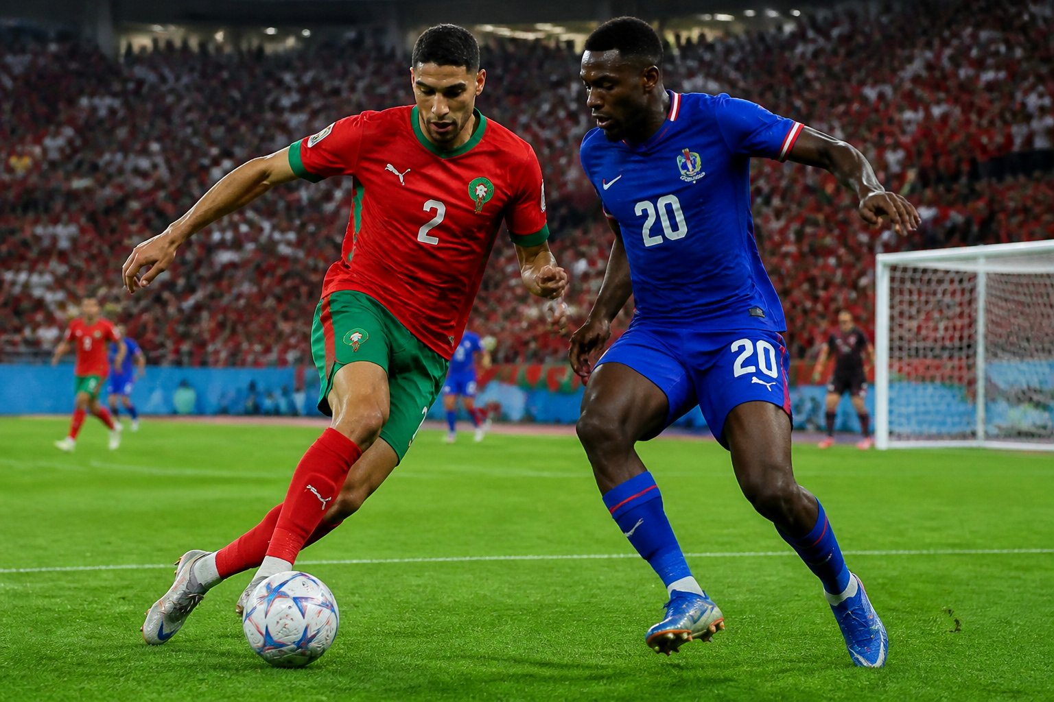 Fas ve Haiti milli takımları arasında bir Dünya Kupası maçında futbolcular top için mücadele ediyor, tribünlerde taraftarlar yer alıyor.